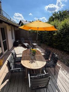 a wooden table and chairs with an umbrella on a deck at ChiemseeLeben in Breitbrunn am Chiemsee