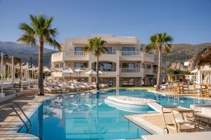 a pool at a resort with chairs and palm trees at Parthenis Beach, Suites by the Sea in Malia