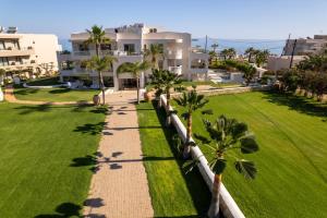 a lawn with palm trees in front of a building at Parthenis Beach, Suites by the Sea in Malia