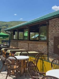 a patio with tables and chairs and a building at GUZIJAN seosko domaćinstvo in Šipovo