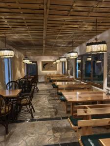 a restaurant with wooden tables and chairs and windows at GUZIJAN seosko domaćinstvo in Šipovo