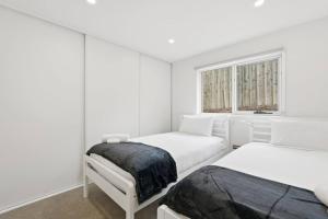 a white bedroom with two beds and a window at Stylish Rosetta Waterview Stay in Rosetta