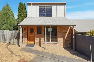 a brick house with a wooden door in a yard at Cosy Unit Near MONA in Claremont +11 photos