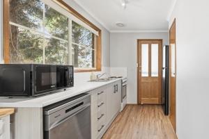 a kitchen with a sink and a microwave at Cosy Unit Near MONA in Claremont