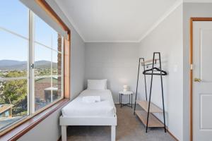 a white room with a bed and a window at Cosy Unit Near MONA in Claremont