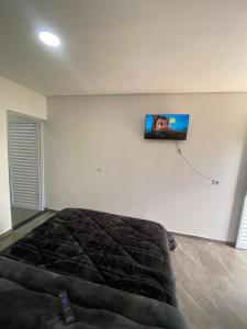 a bedroom with a bed and a tv on the wall at Pousada San Matheus in São Miguel Arcanjo