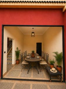 a patio with a table and chairs and a red wall at Villa lumina , Marrakech in Oulad Mazoug