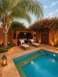 a swimming pool in a yard with two chairs and a tv at Villa lumina , Marrakech in Oulad Mazoug