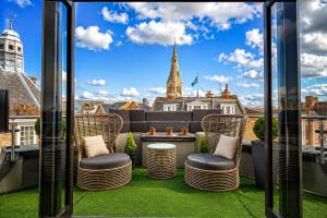 a balcony with two chairs and a table with a view of a city at Villare Hotel Leicester City Centre in Leicester