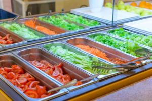 a buffet filled with different types of vegetables in trays at Hotel Colorado in Rimini +33 photos