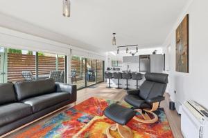 a living room with a black couch and a rug at Riverview Townhouse Retreat in Lindisfarne