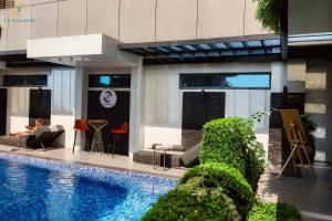 a building with a swimming pool and a person sitting in a chair at Hotel La Falaise Bonapriso in Douala