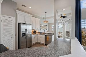 a kitchen with white cabinets and a stainless steel refrigerator at Gulf-View Townhome Hot Tub 2-Min Beach Walk in Galveston