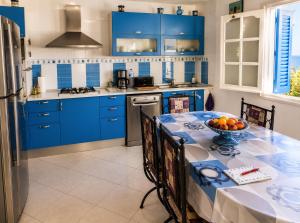 a kitchen with blue cabinets and a table with a bowl of fruit at Villa Jasmin Zarzis in Zarzis