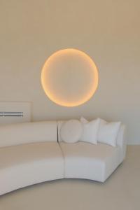 a white couch in a room with a light fixture at VOUNO Santorini Private Villas in Pyrgos +38 photos