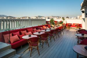 a balcony with a red couch and tables and chairs at Vincci Mae in Barcelona