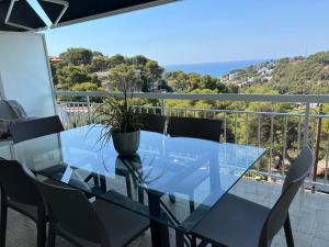 a glass dining table and chairs on a balcony at Panoramic 4 Apartments 2B in Castelldefels