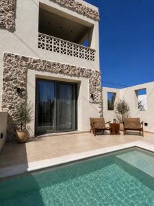a villa with a swimming pool and a house at Ethos Suites in Agios Prokopios