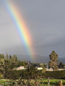 a rainbow in the sky over a field at Quinta San Agustin in Latacunga