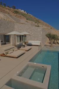 a villa with a swimming pool with chairs and umbrellas at VOUNO Santorini Private Villas in Pyrgos