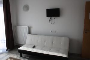 a white couch in a room with a tv on the wall at Pension Kirchenwirt in Niederaichbach