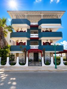 a blue and white building with palm trees in front at Kiki by the sea Villa in Paralia Katerinis