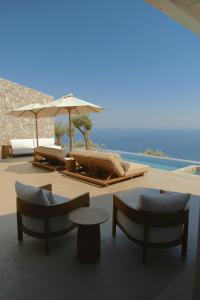 two lounge chairs and umbrellas next to a pool at VOUNO Santorini Private Villas in Pyrgos
