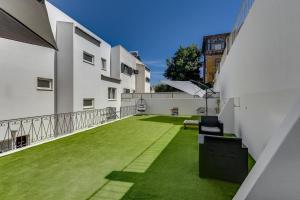 an outdoor patio with green grass and white buildings at Maison Azur Oeiras Beach in Oeiras