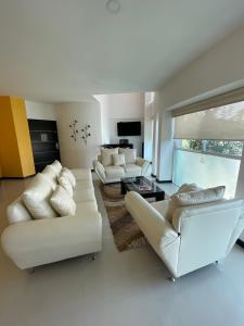 a living room with white furniture and a large window at Penthouse with Pool, Gym & A/C in Querétaro