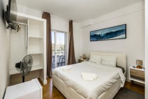 a bedroom with a white bed and a fan at Maison Azur Oeiras Beach in Oeiras