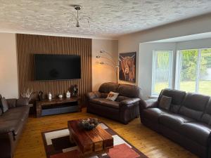 a living room with leather furniture and a flat screen tv at Gleneden House in Tore
