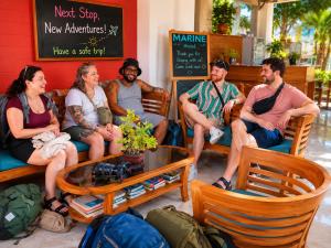 a group of people sitting on benches in a restaurant at Marine Hostel at Negombo Beach in Negombo