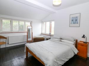 a white bedroom with a large bed and windows at Faraway in Rhosneigr