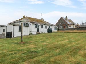 a white house with a grass field in front of it at Faraway in Rhosneigr