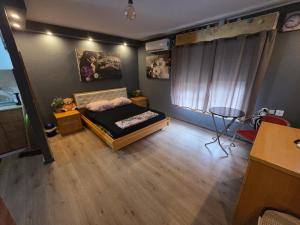 a bedroom with a bed and a table and a window at Slice of life in Qiryat Motzkin