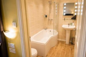 a bathroom with a toilet and a tub and a sink at Wakefield Limes Lodge in Wakefield
