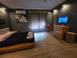 a bedroom with a bed and a dresser with a television at Slice of life in Qiryat Motzkin
