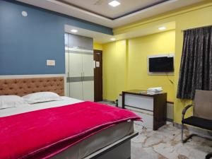 a bedroom with a bed and a desk and a television at NHM Stays in Garui
