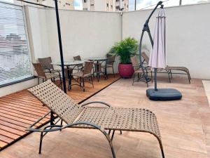 a patio with chairs and tables and an umbrella at Apartamento Garden com churrasqueira área Gourmet in Bauru