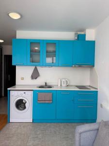 a kitchen with blue cabinets and a washing machine at Byla Central Studio in Byala