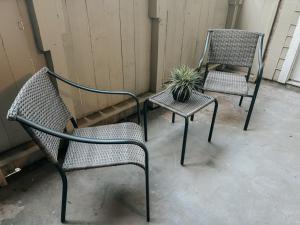 two chairs and a potted plant sitting on a porch at Spacious Poolside Oasis - Easy Access and Garage in Corpus Christi