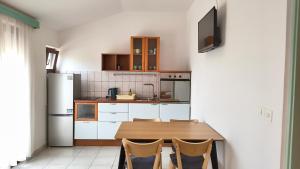 a kitchen with a wooden table and a refrigerator at Apartmani Nina in Starigrad