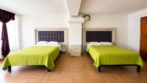 two beds with green sheets in a room at Hotel Plaza Tapatia in Guadalajara