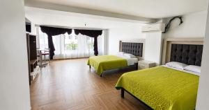 a hotel room with two beds and a table at Hotel Plaza Tapatia in Guadalajara