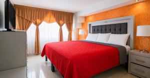 a bedroom with a red bed with a red blanket at Hotel Plaza Tapatia in Guadalajara