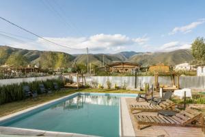 a swimming pool with chairs and mountains in the background at Amplios Departamentos con Vistas a los cerros - Patio, Asador y Pileta in Tafí del Valle
