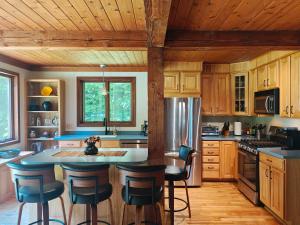a kitchen with wooden cabinets and a island with bar stools at Authentic VT Chalet, Hot tub, Fire pit, Mt Snow in Dover