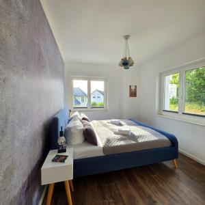a bedroom with a blue bed and two windows at Villa Eckhart in Göhren