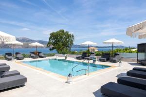 a swimming pool with chairs and umbrellas at Remenata in Lixouri