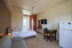 a bedroom with a bed and a couch and a refrigerator at Remenata in Lixouri